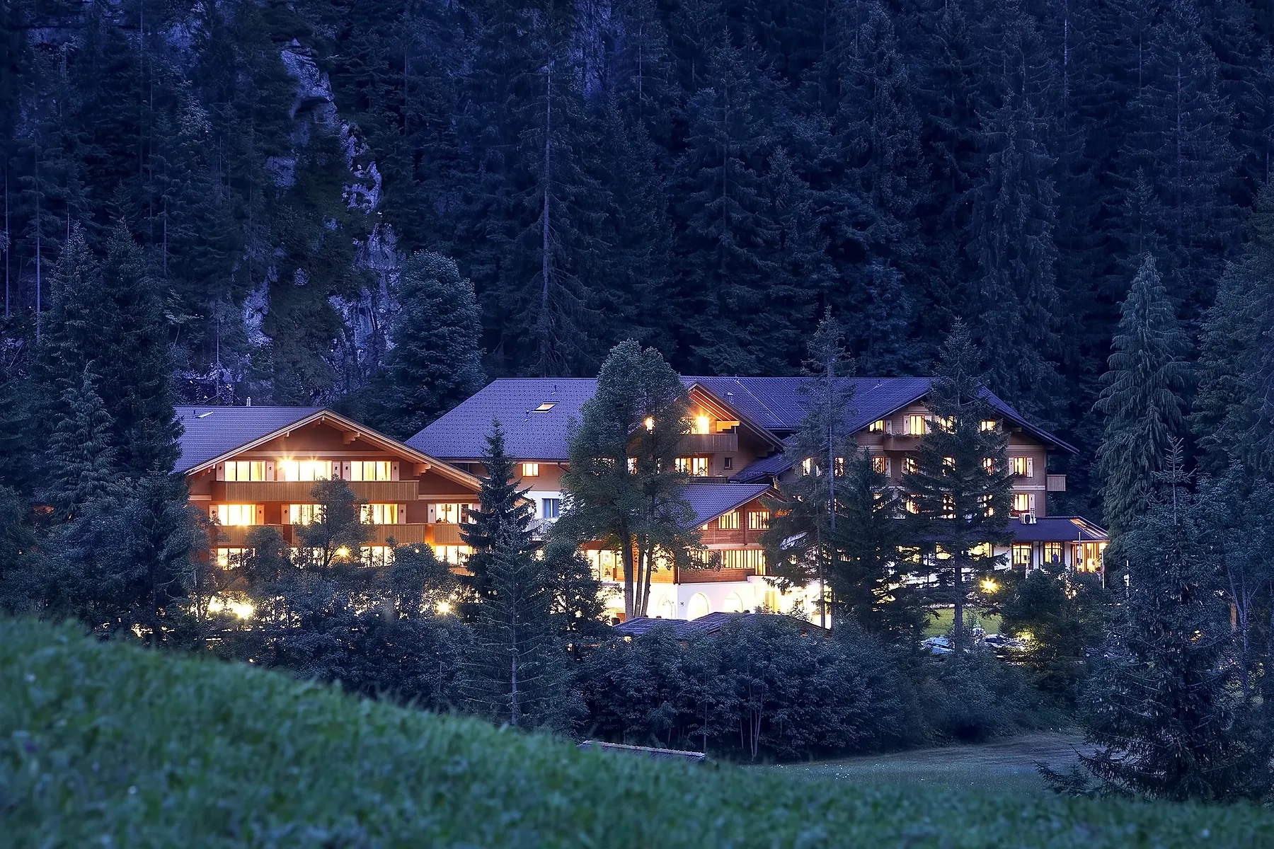 Das Waldhotel Doldenhorn am Abend vor dem Wald, alle Fenster erleuchtet