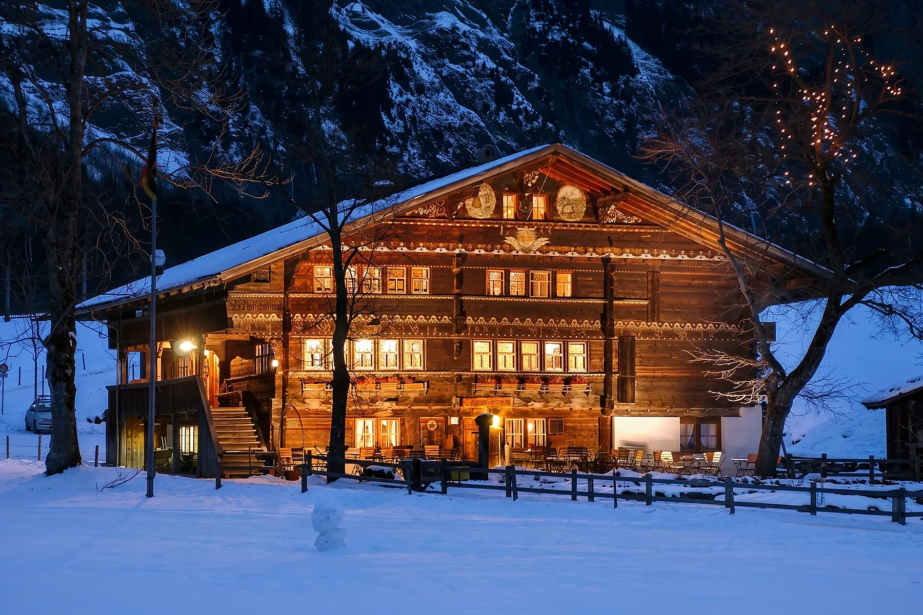 Der Landgasthof Ruedihus im Schnee zur blauen Stunde, die Stuben erleuchtet