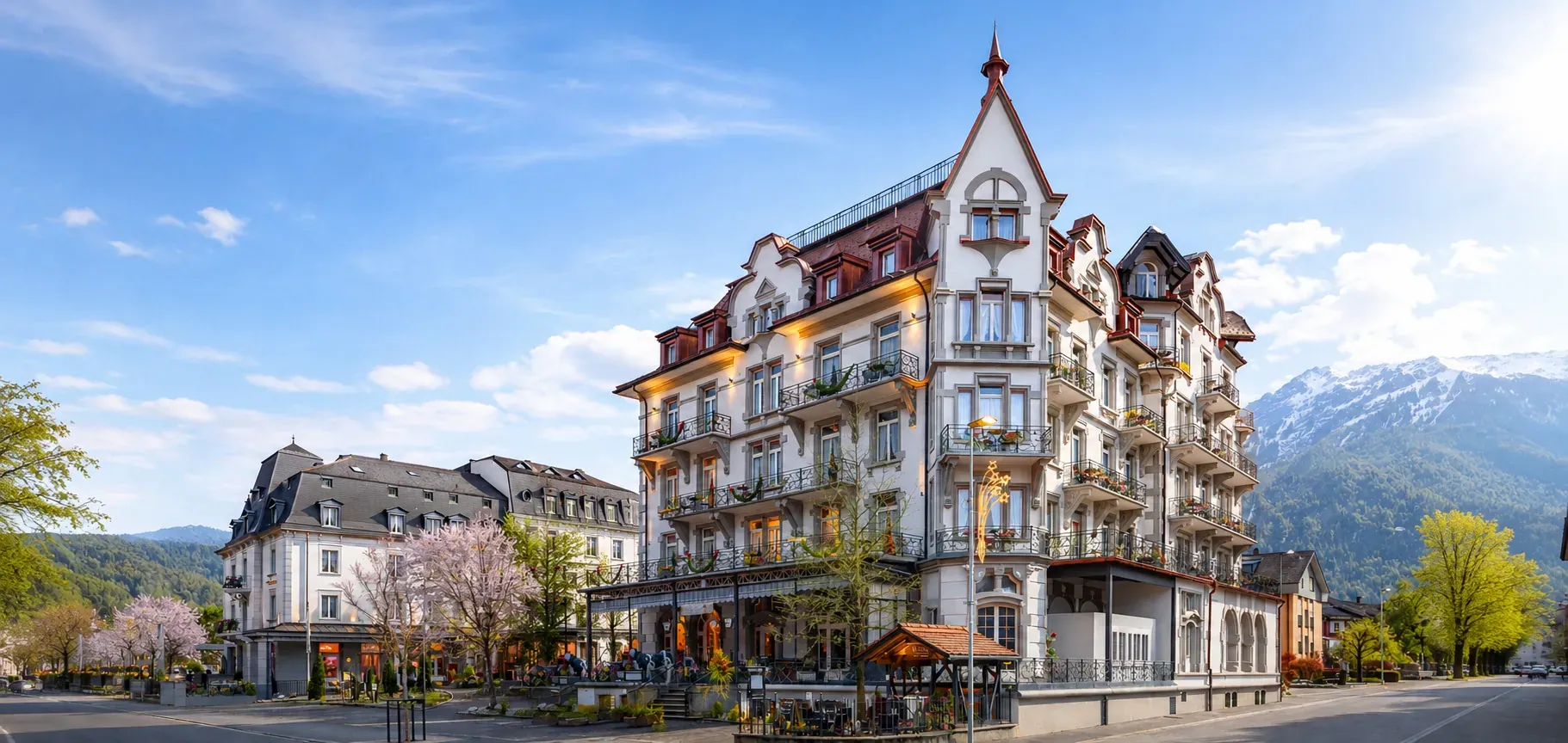 Das Carlton-Europe am Höheweg in Interlaken: zwei Jugendstilhäuser, davor blühende Bäume