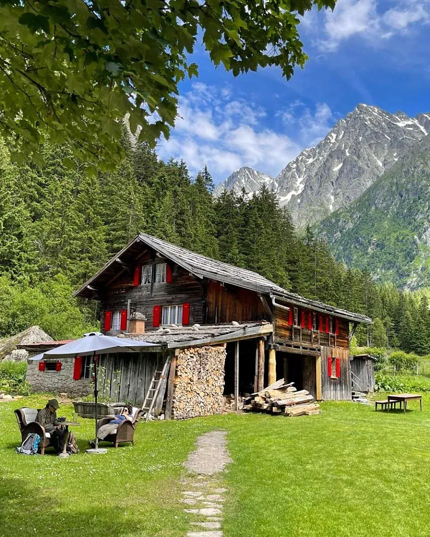 Das alte Holzhaus des Berghotels Gasterntal auf der Wiese, dahinter die Felsen