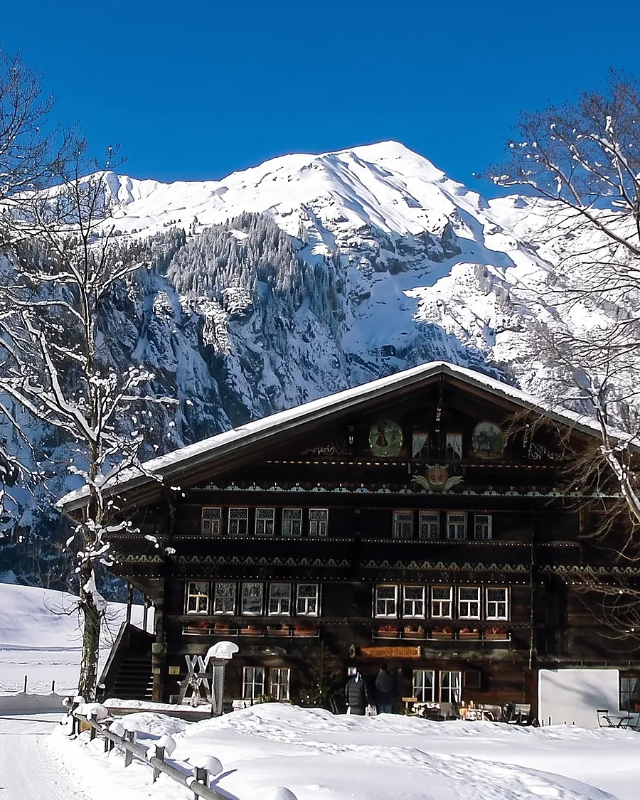Der Landgasthof Ruedihus im Schnee, dahinter die Berge