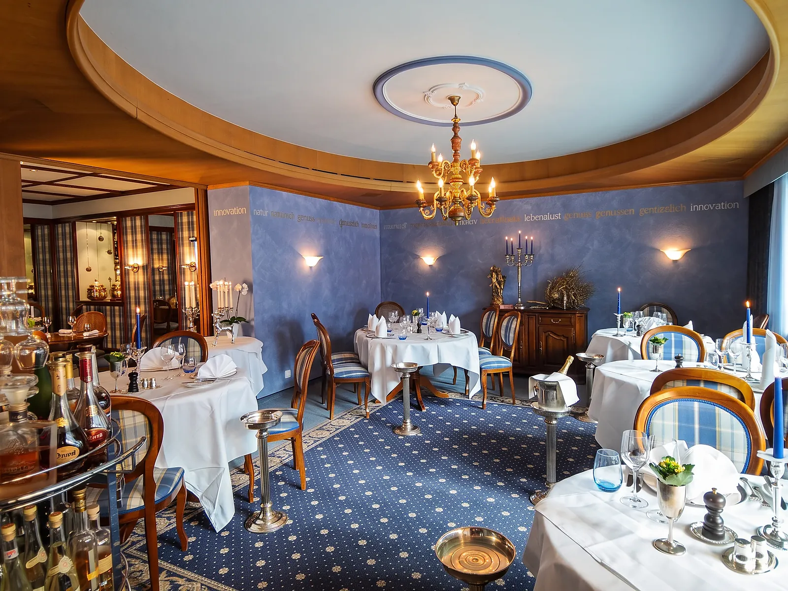 Restaurant mit blauem Teppich, Leuchter und weiss gedeckten Tischen