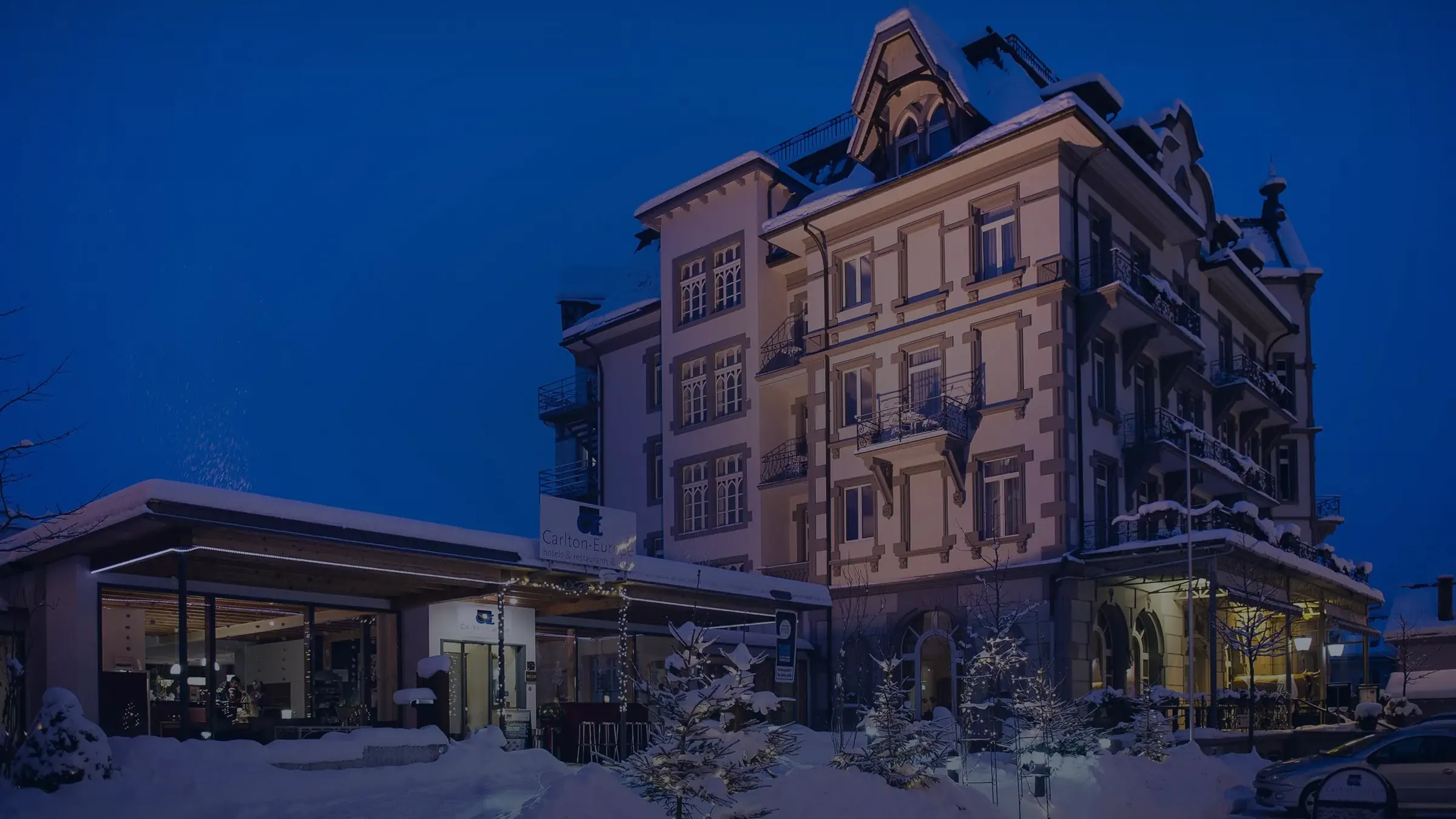 Das Carlton-Europe in Interlaken zur blauen Stunde im Schnee, die Fenster erleuchtet