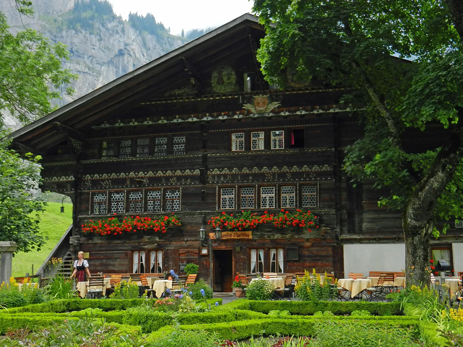 Die Fassade des Ruedihus mit Butzenscheiben und Geranien, davor der Garten
